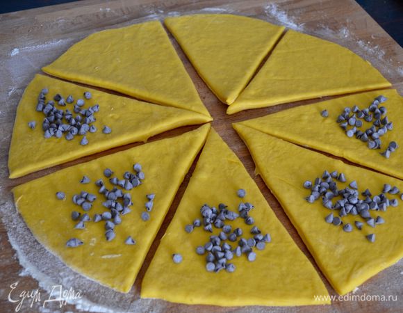 По истечение указанного времени тесто выложить на рабочую поверхность, присыпанную мукой. Обмять и раскатать в круг. Нарезать тесто на 8 сегментов. На каждый треугольник теста положить кусочки шоколада (как у меня) или любую начинку по желанию.