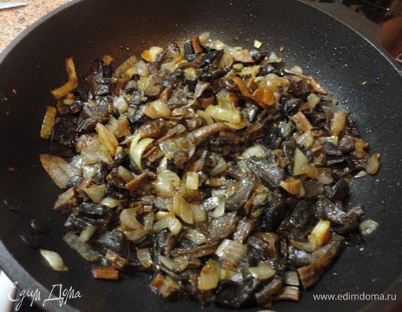 На смеси сливочного и растительного масел обжарить лук до золотистого цвета, добавить грибы, потушить пару минут, посолить и поперчить.
Включить духовку для нагрева до 220°C.