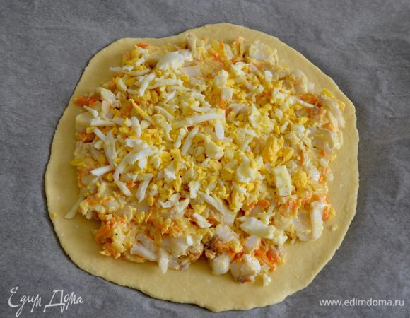 Посолить и поперчить по вкусу. Добавить майонез и перемешать. 
Тесто разделить на 2 части. Одну часть раскатать в лепешку диаметром 20-22 см, выложить на противень, застеленный пекарской бумагой. Сверху выложить рыбную начинку. А затем — слой из натертого на крупной терке яйца... 
