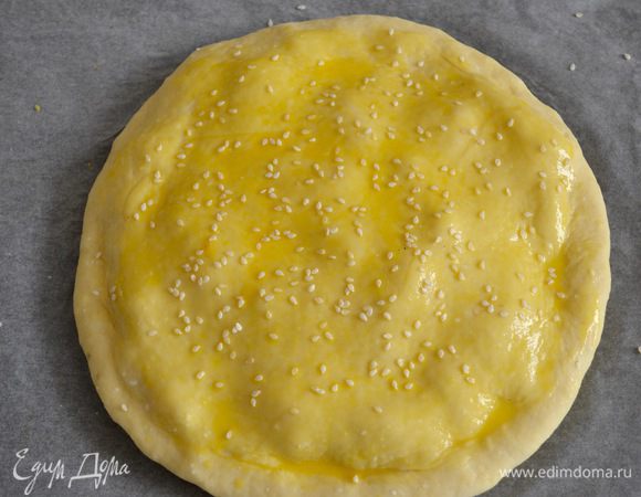 Смазать верх пирога яичным желтком, смешанным с небольшим количеством воды. Сверху присыпать кунжутом.