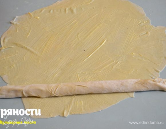 Следующий кусочек теста так же раскатываем и смазываем. На него кладем предыдущий скатанный в рулет кусок на самый край и начинаем заворачивать в рулет первый кусок, как бы оборачивая его вторым.