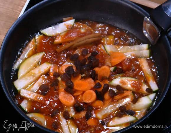 В сковороду с цукини добавить морковь, палочку корицы и изюм, посыпать паприкой и солью, все перемешать и еще немного обжарить.