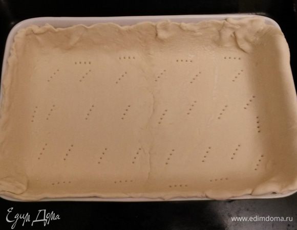 Слоеное тесто раскатываем по размеру формы, формируя высокие бортики. Накалываем вилкой.