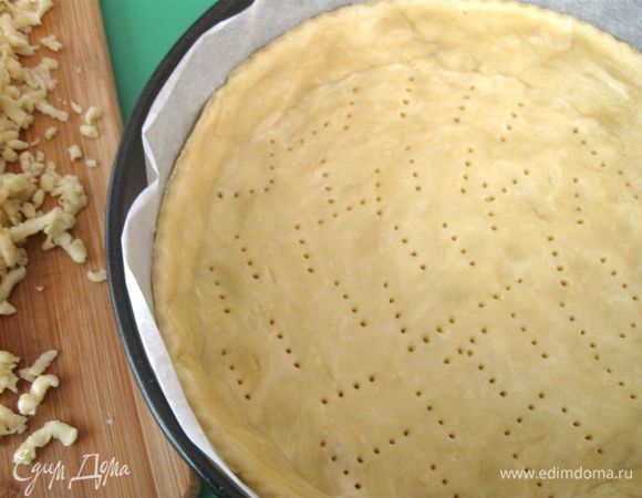 Форму закрыть пекарской бумагой (дно и борта), часть теста раскатать и положить на дно, сделать бортики из теста, прикрепить к донышку, на дне сделать проколы вилкой. Край бортиков обработать колесиком для пиццы. Убрать форму с тестом в холодильник минут на 20-30. 
