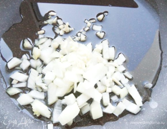 Пока рис варится, не теряя времени, в сковороде разогреть масло, обжарить нарезанный кубиками лук, чеснок около двух минут на среднем огне.