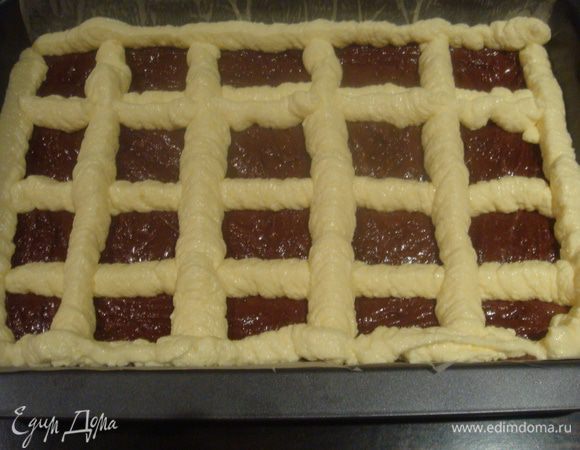 С помощью кондитерского мешка сделать сетку из крема на тесте.