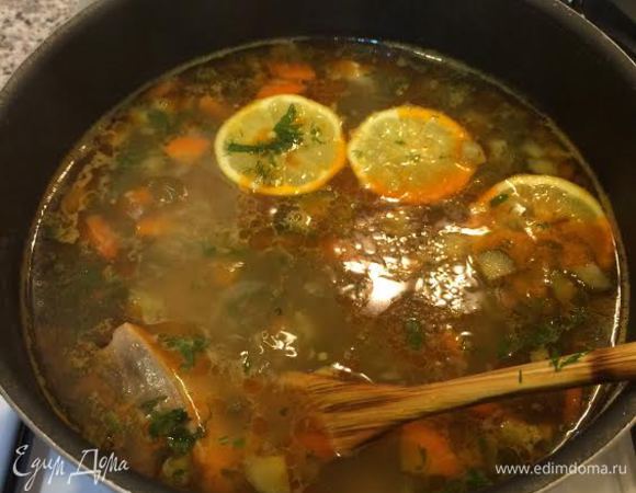 Добавить оливки и каперсы. Зелень мелко нарезать. Зелень и лимон добавить в суп. Посолить, поперчить и снять с огня.