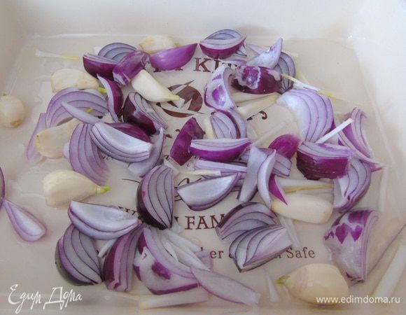 Лук (4 шт) и чеснок очистите. Лук нарежьте на четвертинки, чеснок целый уложите на дно смазанной формы для запекания.