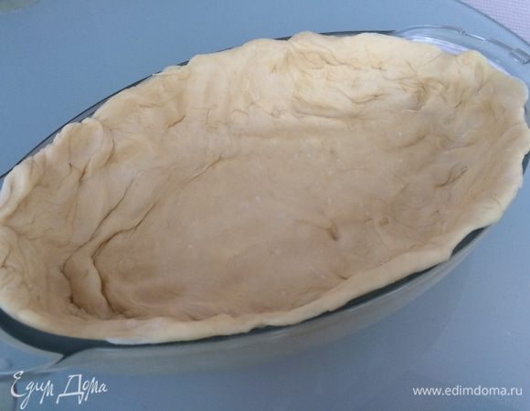 Форму для запекания смажьте маслом, положите тесто и разровняйте по дну и стенкам плотным слоем. Убедитесь, чтобы не было дырок, и пласт получился ровным.
