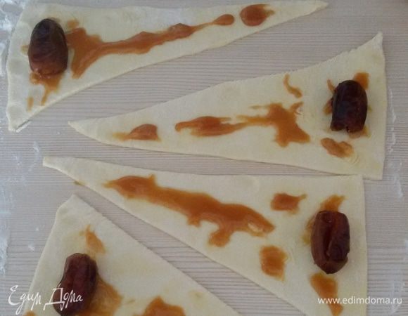 Смазать каждый треугольник небольшим количеством меда и на широкий край положить финик без косточки.

