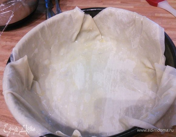 Форму для выпечки смазать маслом. Посыпать сухарной крошкой. Три листа теста фило поочерёдно смазать растопленным сливочным маслом, выложить один на другой и аккуратно переложить в форму.