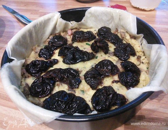 Выложить половину начинки, немного утрамбовать. Сверху поместить чернослив. 