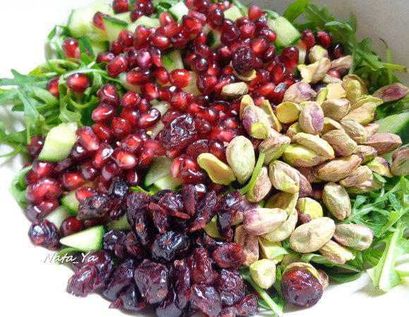 Добавить фисташки и сушеную клюкву в салат.