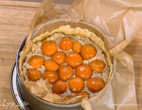 На подпеченный корж тонким слоем выложить марципановую массу, а затем половинки абрикосов срезом вниз.