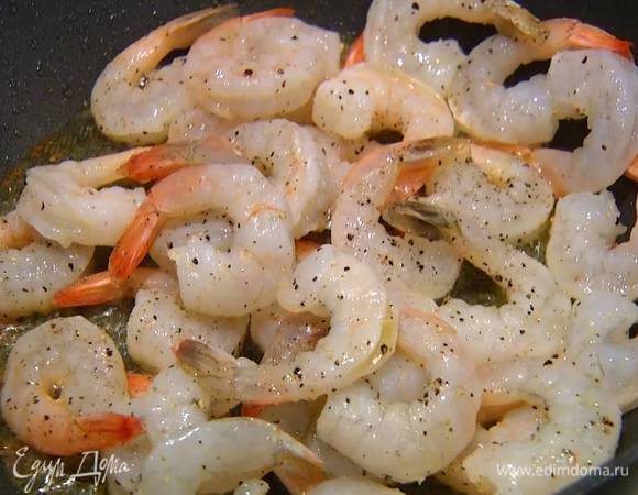 Разогреть в сковороде оставшееся оливковое масло, выложить креветки, посолить, посыпать черным перцем и обжарить.