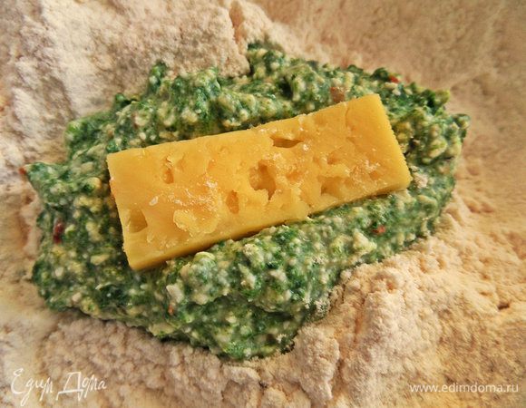 В миску со стаканом муки положить ложку с горкой шпинатной массы. Не переживайте, что она расплывается, так ньокки будут нежнее! Сверху кладём брусочек сыра.