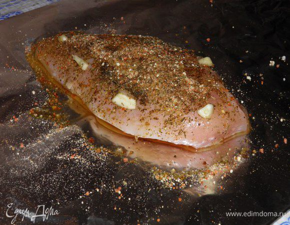 В глубокую чашку насыпать 1 ст. л. соли и залить 1 стаканом воды, перемешать. Погрузить грудку на 2 часа, вынуть, обсушить. Грудку выложить на выстланный фольгой противень, обмазать грудку со всех сторон оливковым маслом, специями, нашпиговать чесноком. 