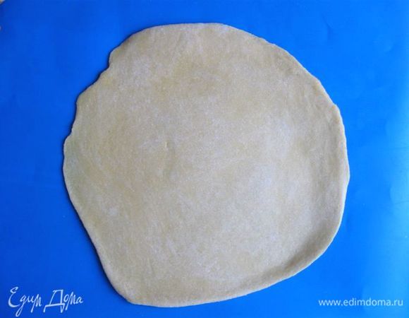 Раскатать тесто скалкой от центра к краям. Переворачивать периодически при раскатывании. Тесто не должно приставать к скалке и к рабочей поверхности.  
