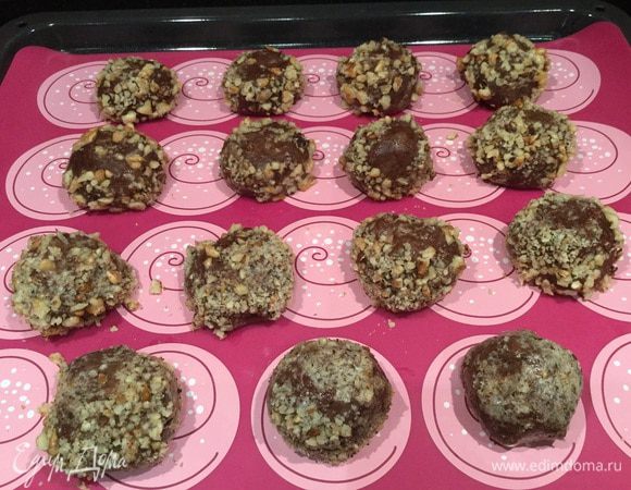 Из теста сформируйте небольшие шарики, обмакните их в белок и обваляйте в орехах. Выложите на застеленный пергаментом или силиконовым ковриком противень.