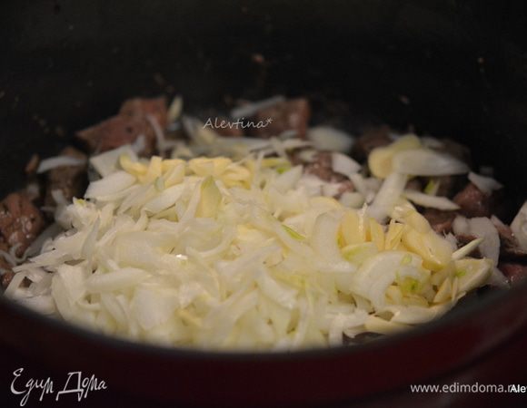 Лук и чеснок очистить и тонко нарезать. Добавить в говядину. Перемешать и обжаривать несколько минут до мягкости лука.