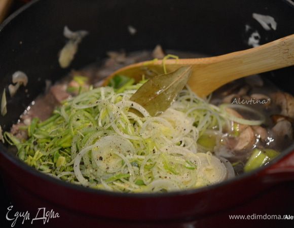 Влить бульон, мелко нарезанный лук-порей колечками. Убавить огонь, закрыть крышкой и тушить 1,5 часа.