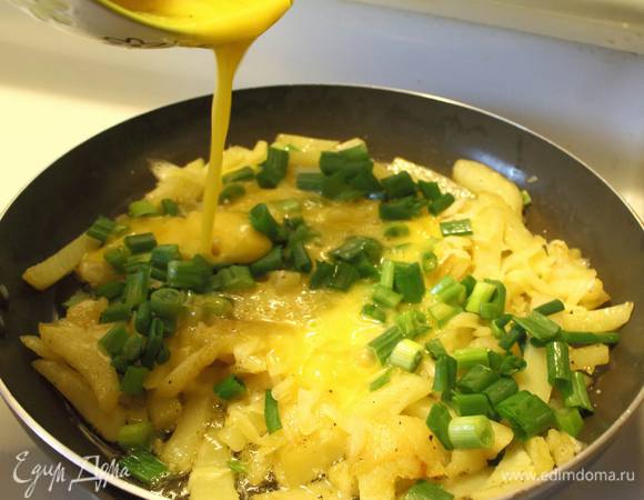 Минуты через две, как отправили белый лучок, посыпаем картофель тертым сыром. Укладываем сверху зеленый лук и заливаем яйцами.
