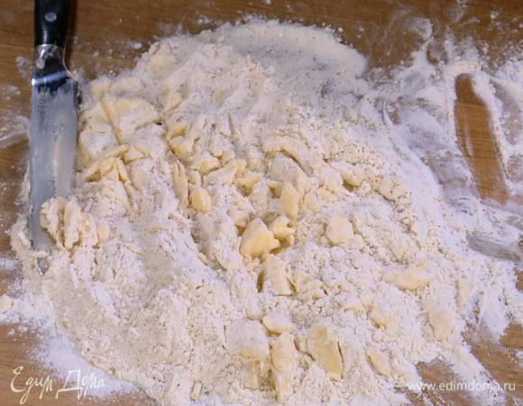 На рабочую поверхность через сито высыпать горкой 250 г муки, сахар и соль, сделать в центре углубление, выложить в него сливочное масло комнатной температуры и ножом порубить все в крошку.