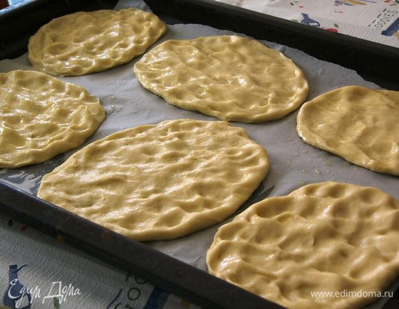 Подготовленные лепешки выкладываем на противень, выстеленный пекарской бумагой. Стамим противень в чуть разогретую духовку. Даем лепешкам подняться минут 40. 