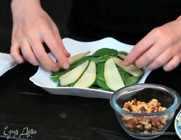 Сложить шпинат горкой, тонко нарезать грушу и выложить на шпинат.