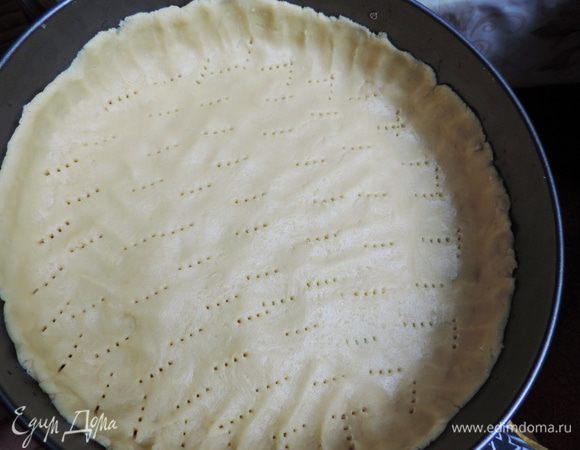 Берем форму 26 см с высокими бортами, желательно разъемную. Дно формы выстилаем пергаментом.
Распределяем тесто по поверхности, формируя бортик чуть больше 2 см, накалываем вилкой.