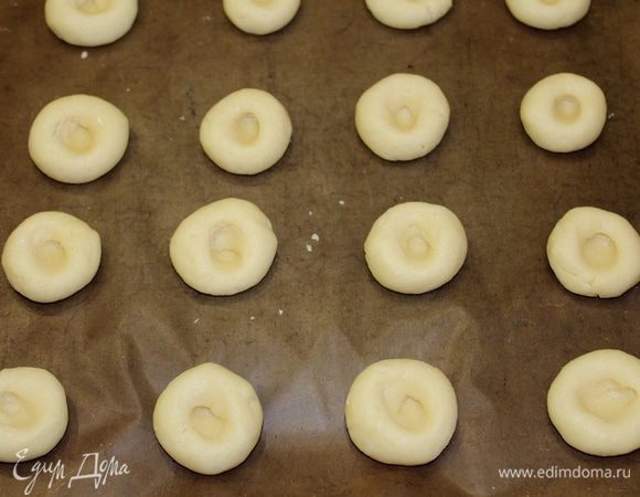 Скатать шарики с грецкий орех, выложить на противень, сделать углубления. Выпекать в разогретой духовке 180°C 5-6 минут.