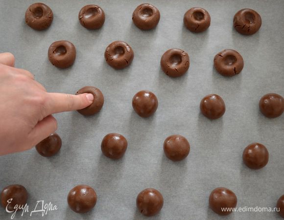 Затем застелить противень пекарской бумагой, достать тесто из холодильника и, отделяя от него кусочки весом около 17 г, сформировать много маленьких шариков (из указанного количества ингредиентов их получается 25 штук). Сделать в каждом шарике углубление.