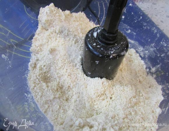 В чашу блендера выложить холодное масло, нарезанное кусочками и муку. Пробить до состояния мелкой крошки.