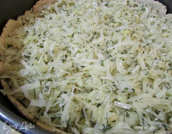 Через 15 минут извлечь корж из духовки. Выложить капусту и аккуратно разровнять по поверхности.