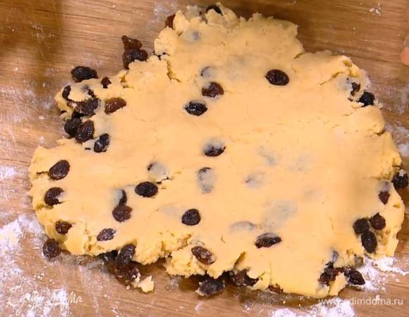 Рабочую поверхность посыпать оставшейся мукой, выложить тесто, вымесить его руками, затем добавить изюм, еще немного вымесить и сформировать из теста пласт толщиной в 1 см.