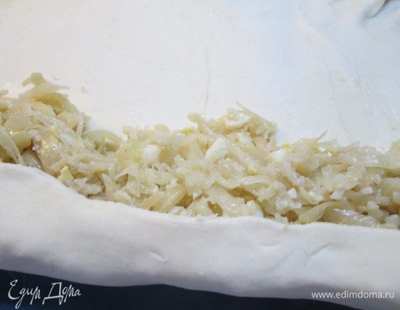 Кладем на край теста начинку (у меня тушеная капуста с репчатым луком и вареными яйцами), заворачиваем тесто туго в рулет и при этом растягиваем в стороны обеими руками — тесто становится еще тоньше.