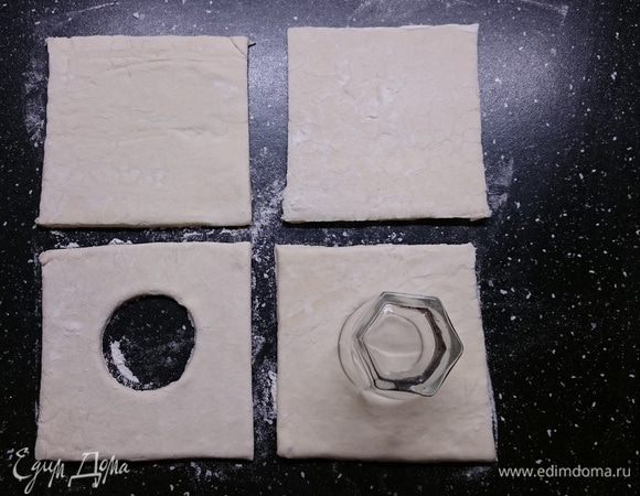 Пласт теста разделить на 4 равных квадрата. В двух квадратах проделать (при помощи рюмки, формочки) отверстие в середине.