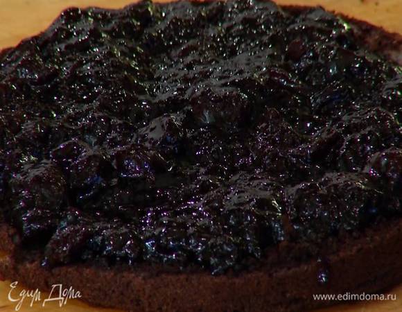 Разрезать бисквит вдоль пополам, нижнюю часть смазать вишневым вареньем, накрыть верхней частью и дать бисквиту пропитаться.