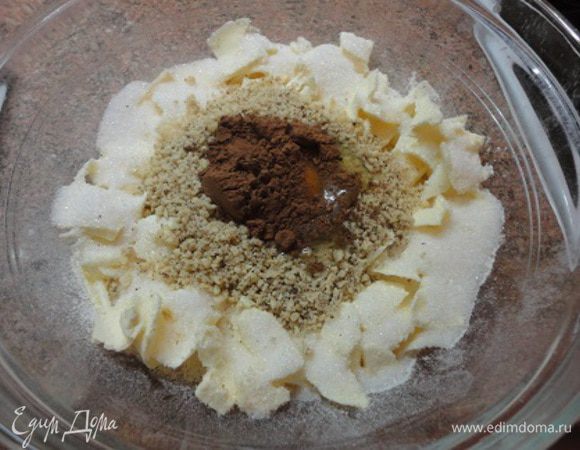 Муку просеять. Очень холодное масло нарезать хлопьями, разместив по краям. Посыпать сахаром. В центр поместить орехи, яйцо, специи и какао. Предлагалось все рубить ножом до мелкой крошки, но я воспользовалась комбайном.