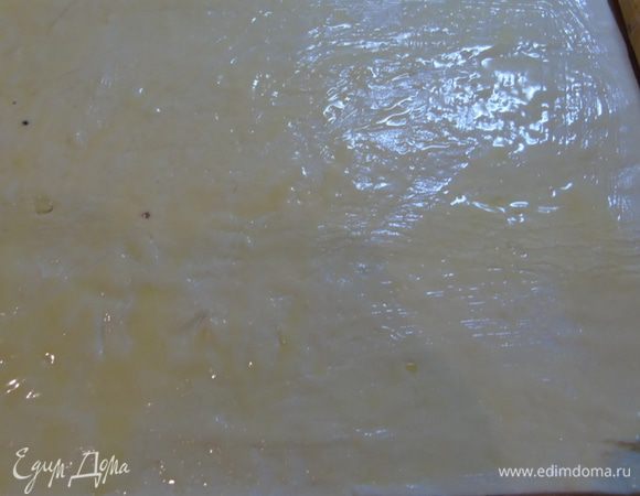 Тесто раскатайте в прямоугольник и смажьте растопленным сливочным маслом.