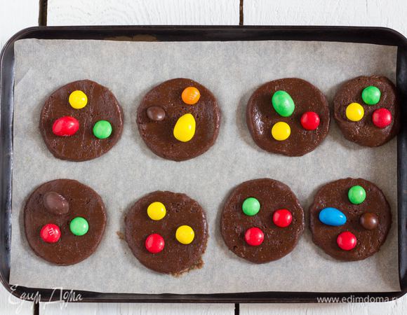 Выстелите противень пергаментом, сформируйте из теста лепешки украсьте конфетками и выложите на противень. Выпекайте печенье при температуре 180°C в духовке 10 минут, затем остудите.