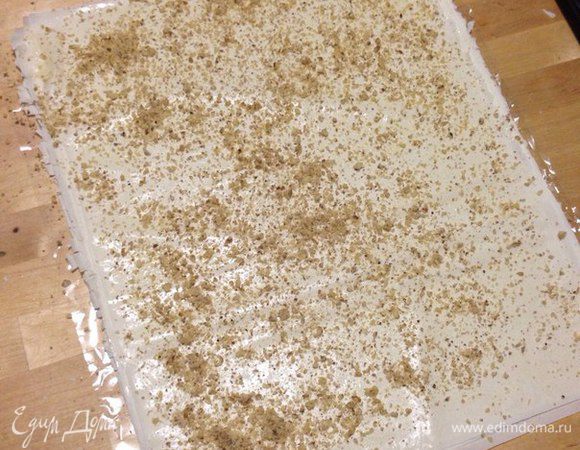 Затем посыпаем молотыми орехами по всей поверхности теста.
И сворачиваем рулет из одного листа теста.