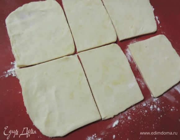 Тесто раскатываем на щедро посыпанной мукой поверхности, само тесто тоже припудриваем мукой, чтобы оно не липло к скалке. 
Для того, чтоб получился эффект слоености не нужно раскатывать тесто очень тонко, 3-4 мм будет в самый раз. Я разделила тесто на 3 части и раскатывала их по одной, каждую деля на 6 квадратов. 