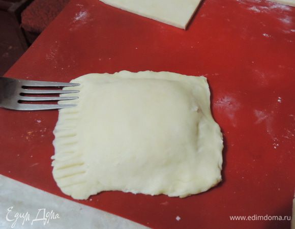 На один квадрат выкладываем начинку, примерно полная столовая ложка, но это зависит от размера квадрата. Накрываем вторым квадратом и защипываем края. Я дополнительно для крепости и красоты придавливаю их вилкой.
Каждую подушечку я опускаю в сахар и придавливаю его, чтобы сахар прилип к тесту. Этот сахар в ингредиентах не значится! Его понадобится примерно 4-5 столовых ложек. 