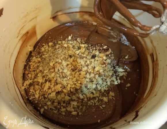 К яйцам постепенно добавляем слегка остывший шоколад и перемешиваем на средней скорости. Затем добавляем орехи и еще раз перемешиваем.
