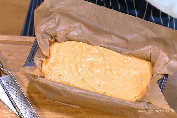 Продолговатую форму для выпечки выстелить пищевой бумагой и выложить тесто.