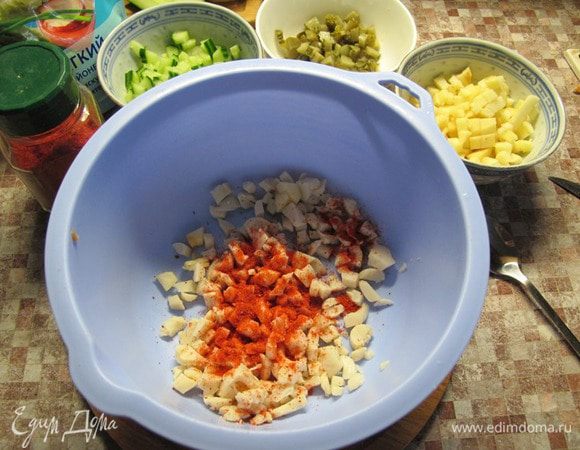 Кальмары перемешать с молотой паприкой. Это придаст им пикантный вкус, красивый розоватый цвет и сделает похожими на крабовое мясо.