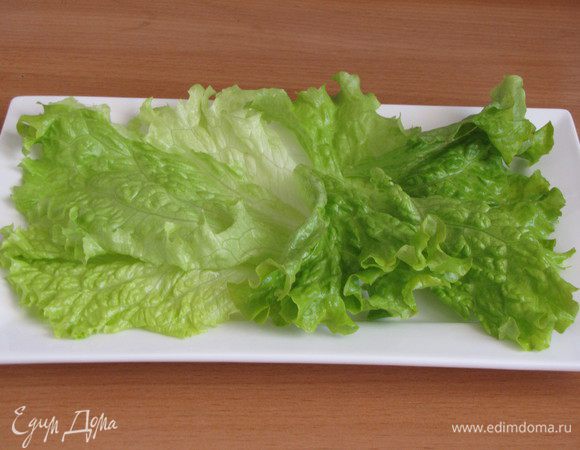 На блюдо или порционную тарелку выложить промытые салатные листья.