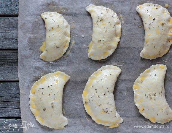 Растопить сливочное масло. Желток смешать с молоком. Смазать поверхность пирожков сперва маслом, затем желтком и присыпать тмином. 