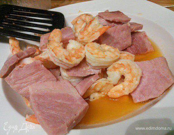 В сковороде разогреть масло и обжарить ветчину и креветки в течении двух  минут. Выложить на тарелку вместе с образовавшимся при жарке соком. 